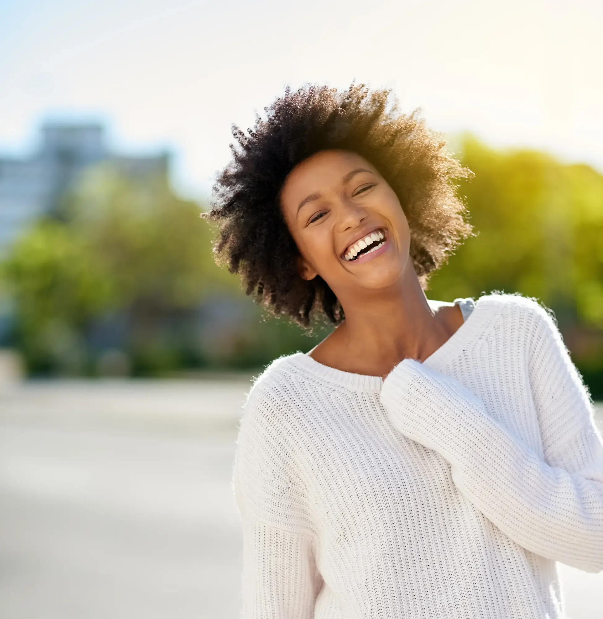 Woman with curly hair smiling outdoors
