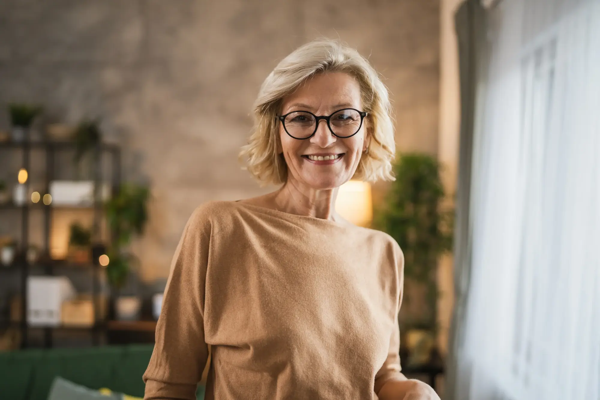 Older woman wearing glasses and smiling indoors