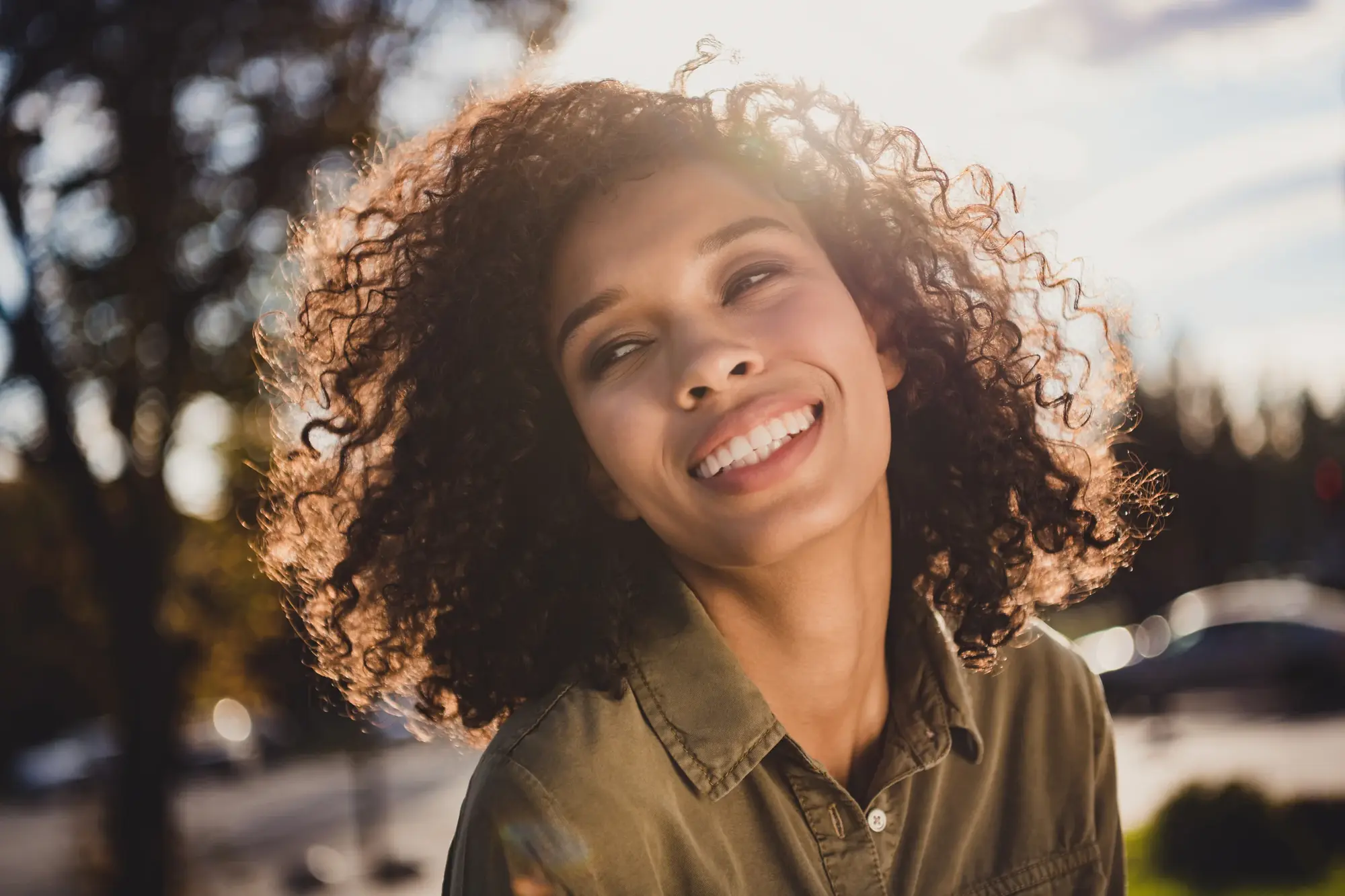 Woman with curly hair smiling outdoors